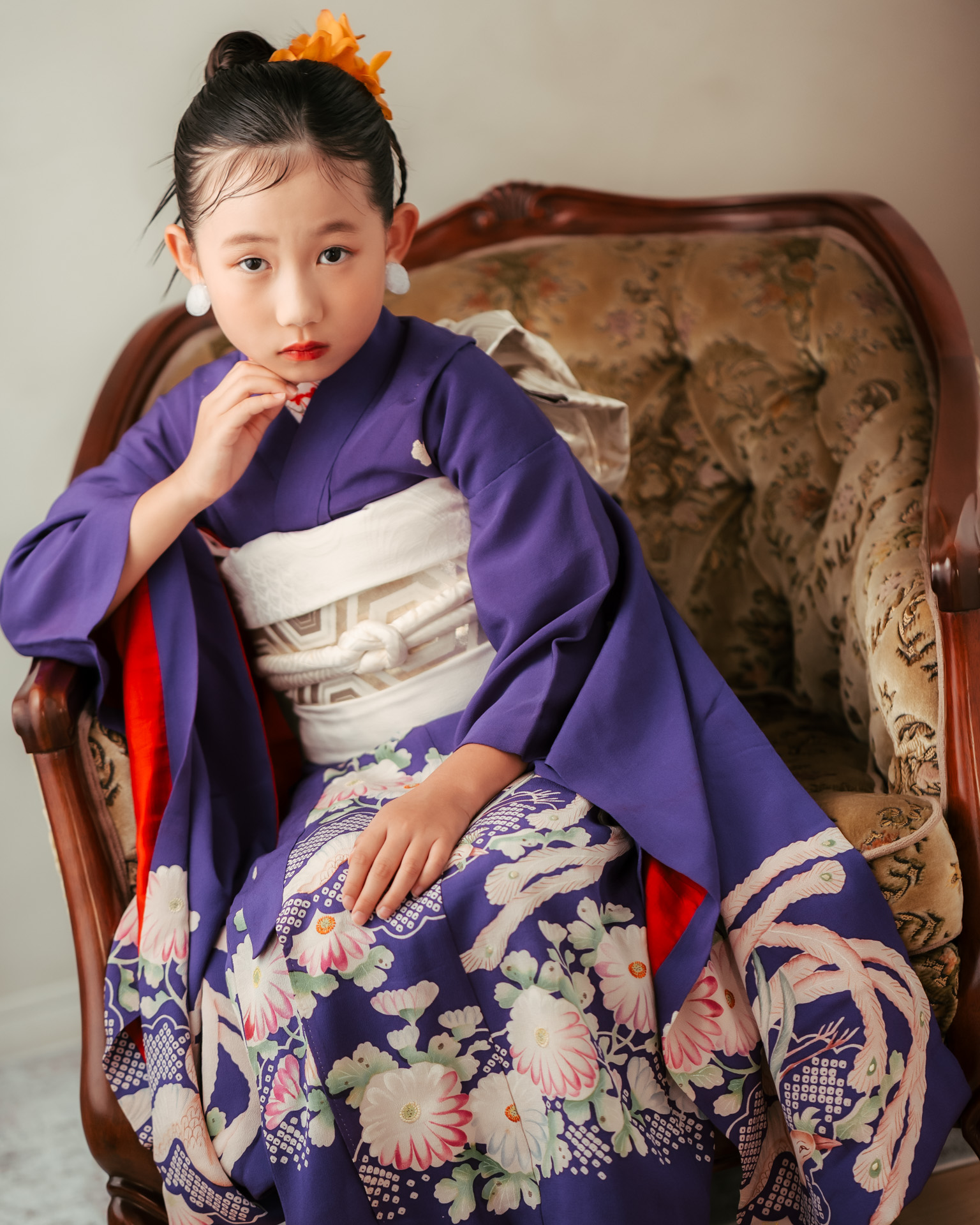 紫の着物を着てアンティークチェアに座る7歳女の子。菊柄と白い帯が印象的な七五三スタイル