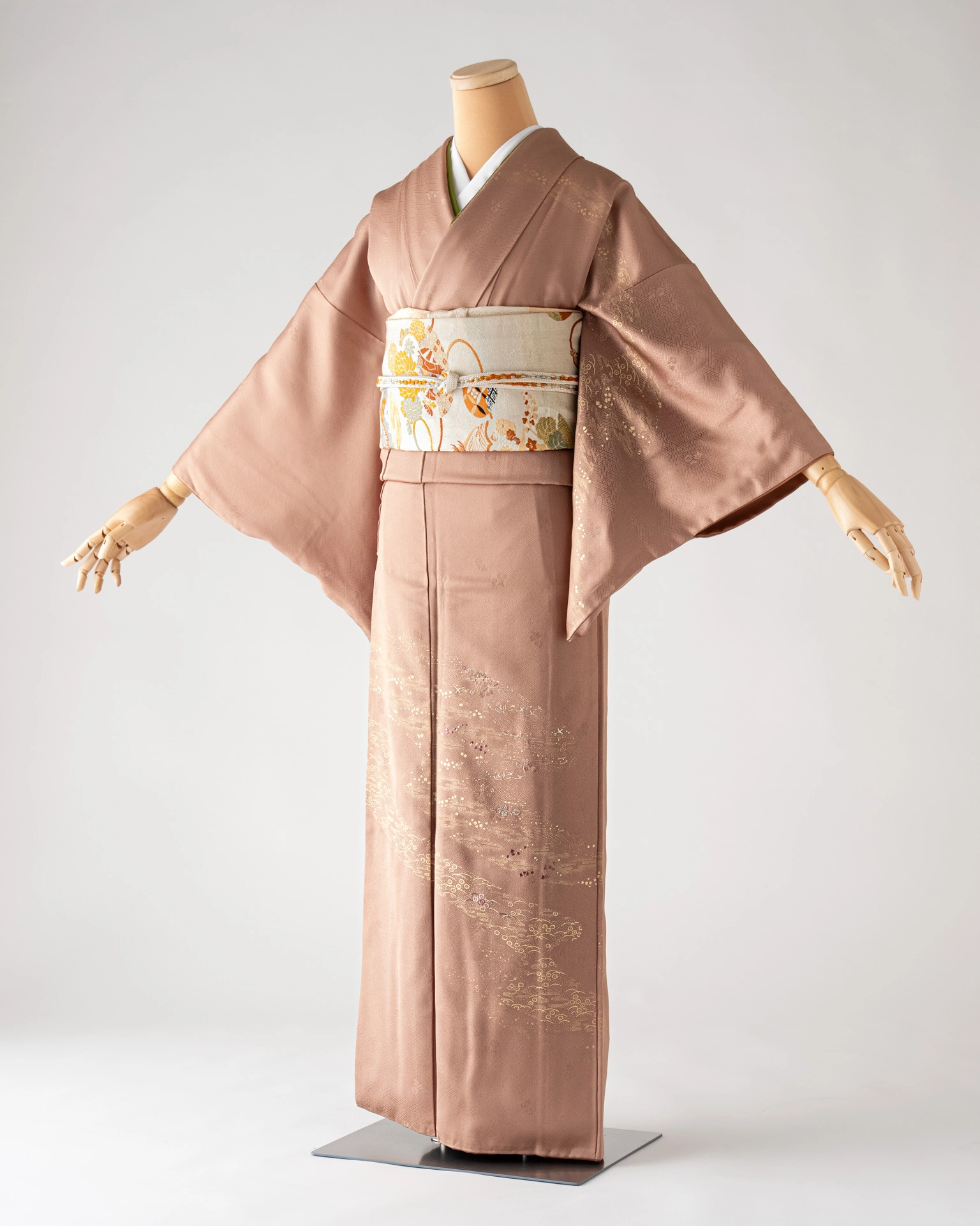 淡い赤茶色の訪問着。上品な光沢のある生地に金彩と繊細な模様が施され、白地に金の帯を締めている。