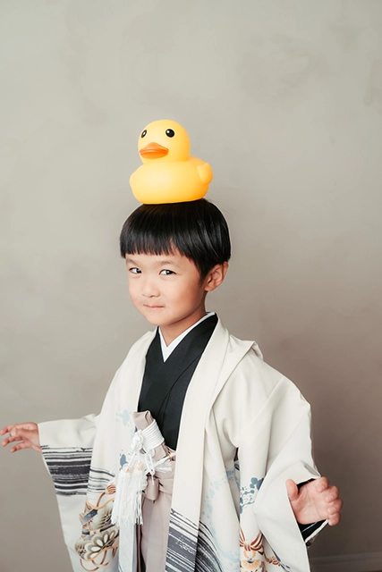 和装姿で頭にアヒルを乗せた男の子のポートレート